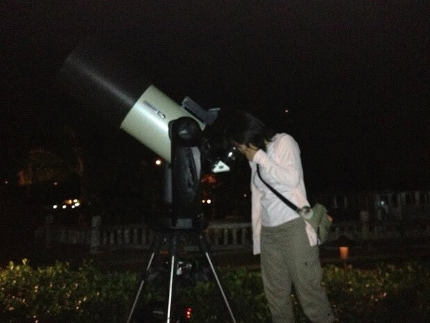 Guest looking through a computerized telescope at the night sky on Oʻahu